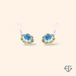 Handcrafted peridot and blue topaz drop earrings set in polished sterling silver, featuring a vibrant blue topaz center surrounded by sparkling green peridot gemstones.